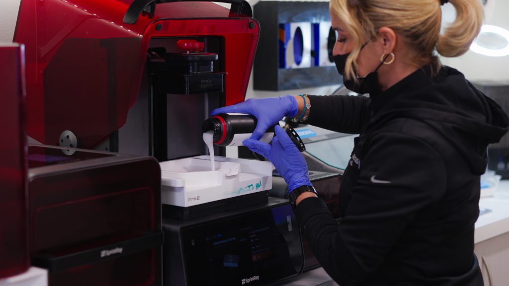 Dental assistant pouring resin into a 3D printer at Limitless Dental Jersey City