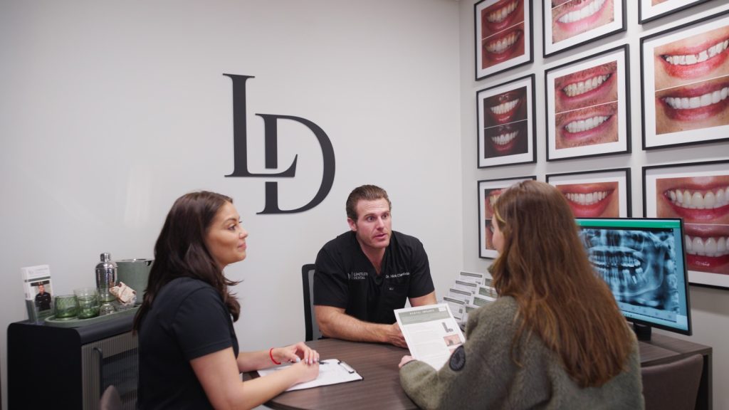 Dr. Nick Ciardiello reviewing a digital smile design on screen with patients at Limitless Dental in Jersey City.