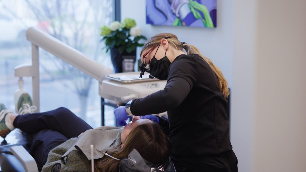 Dr. Nick Ciardiello of Limitless Dental® in Jersey City examining a patient with magnification loupes during a periodontal exam for bleeding gums.
