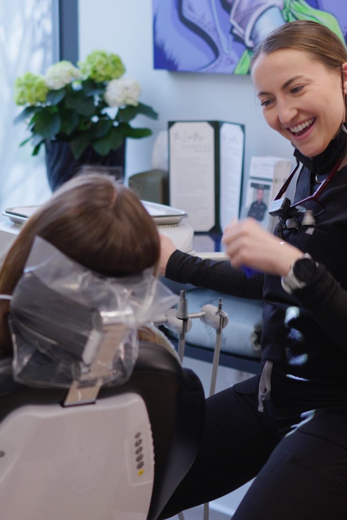 Dr. Nick Ciardiello of Limitless Dental in Jersey City sitting and laughing with a patient mid-conversation in the dental operatory, illustrating the warm tone that helps anxious patients feel at ease.