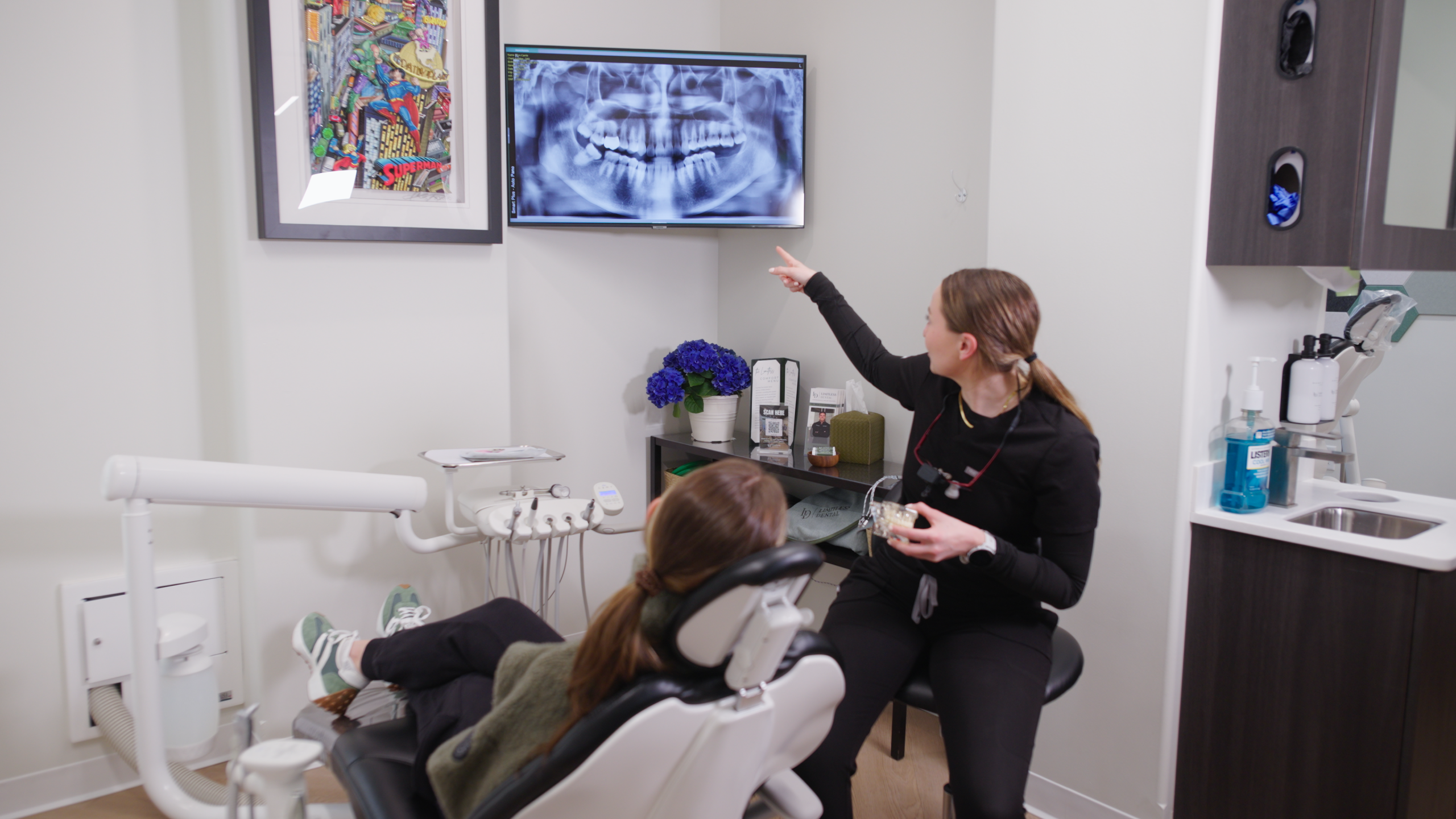 Dr. Nick Ciardiello pointing at a panoramic dental x-ray on a screen while holding a tooth model at Limitless Dental® in Jersey City