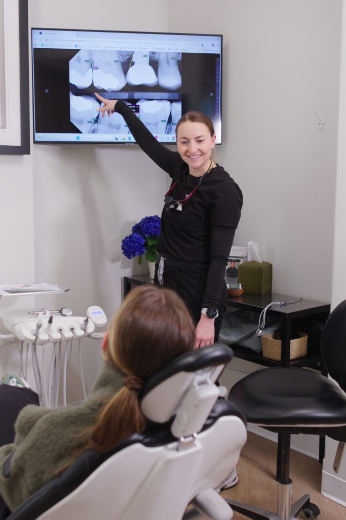 Dr. Nick Ciardiello pointing at a patient x-ray on screen, explaining findings to a seated patient at Limitless Dental in Jersey City.