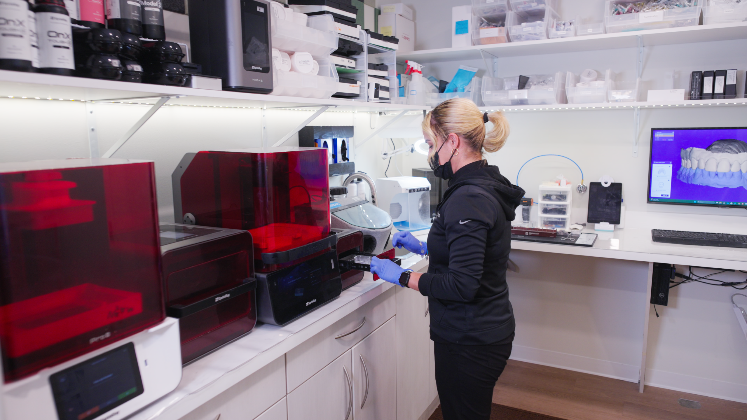 Limitless Dental® lab tech in Jersey City inserting a printed dental tray into a 3D printer with a patient teeth scan on screen, showing the in-house digital workflow Dr. Nick uses for same-day restorations.