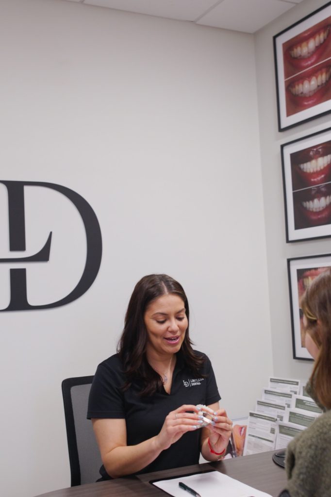 Limitless Dental team member holding a clear aligner tray during a consultation in Jersey City, NJ