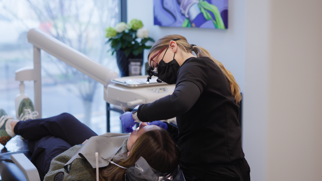 Dr. Nick Ciardiello of Limitless Dental in Jersey City examining a patient in the dental chair using magnification loupes during an emergency consult.