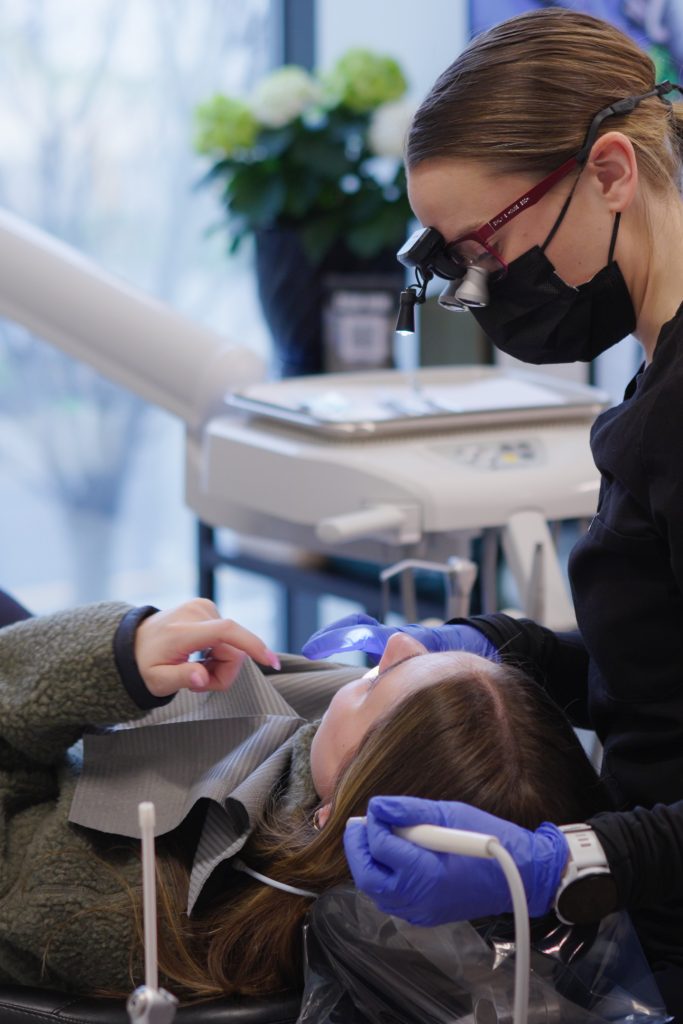 Dr. Nick Ciardiello at Limitless Dental in Jersey City examining a patient with dental magnification loupes during a root canal or extraction consultation